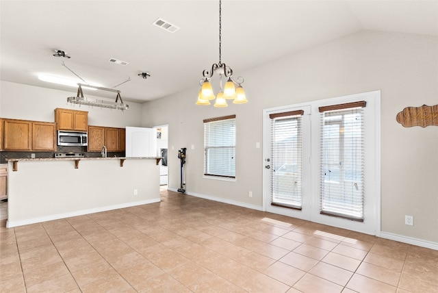 kitchen with a kitchen breakfast bar, light tile patterned floors, pendant lighting, and a notable chandelier