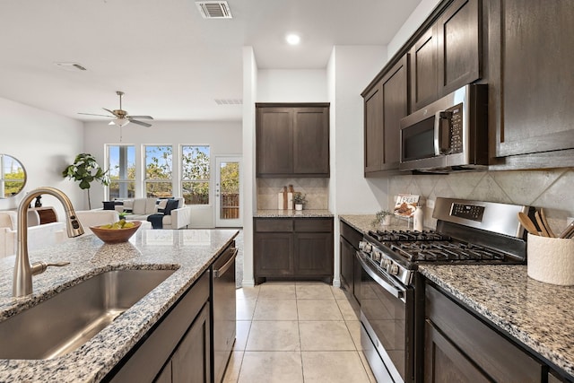 kitchen with appliances with stainless steel finishes, backsplash, light stone counters, and sink