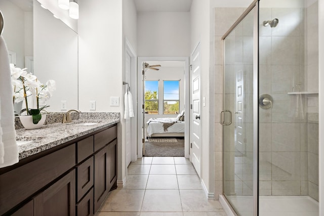 bathroom with tile patterned floors, ceiling fan, a shower with door, and vanity