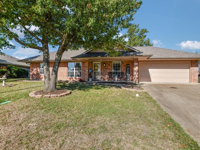 single story home featuring covered porch, a garage, and a front yard