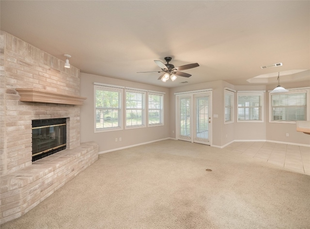 unfurnished living room with ceiling fan, a fireplace, and light colored carpet