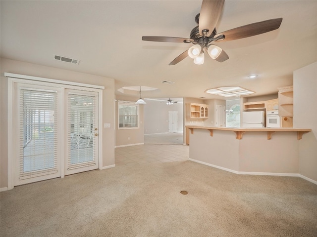 unfurnished living room with light colored carpet and ceiling fan