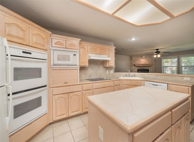 kitchen with tile counters, light brown cabinets, white appliances, and sink