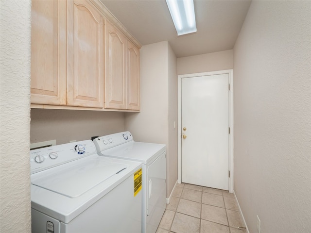 washroom featuring washer and dryer, light tile patterned flooring, and cabinets