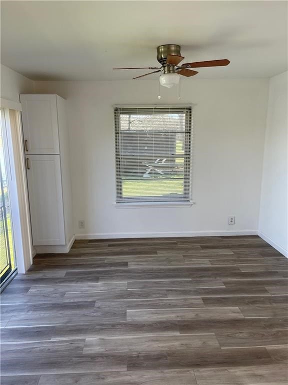 spare room with plenty of natural light, ceiling fan, and dark wood-type flooring