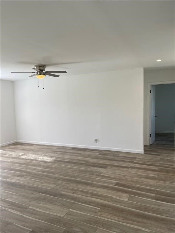 unfurnished room with ceiling fan and dark wood-type flooring