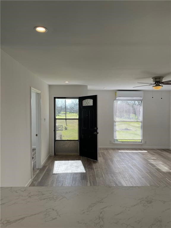 entryway featuring a wall unit AC, ceiling fan, and hardwood / wood-style flooring