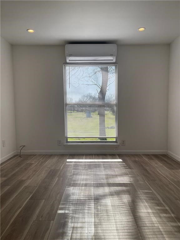 unfurnished room featuring a wall mounted air conditioner and dark hardwood / wood-style flooring