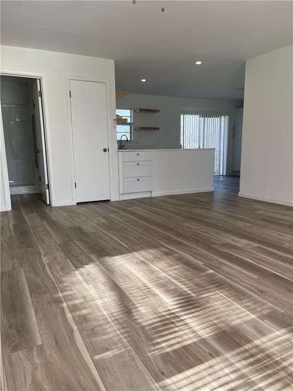 unfurnished living room with dark hardwood / wood-style flooring, a healthy amount of sunlight, and sink