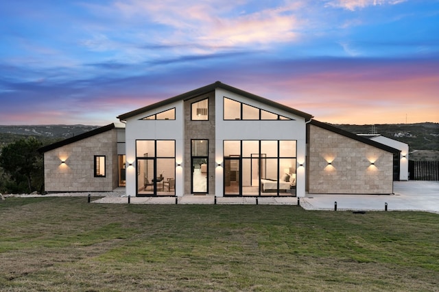 back house at dusk featuring a yard