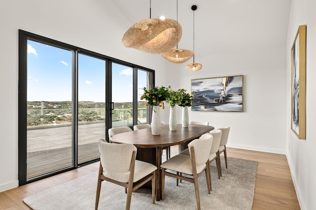 dining area featuring light wood-type flooring and a towering ceiling