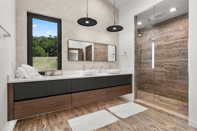 bathroom with tiled shower, hardwood / wood-style floors, and vanity