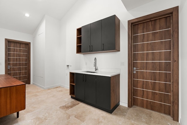 interior space featuring dark brown cabinets, sink, and vaulted ceiling