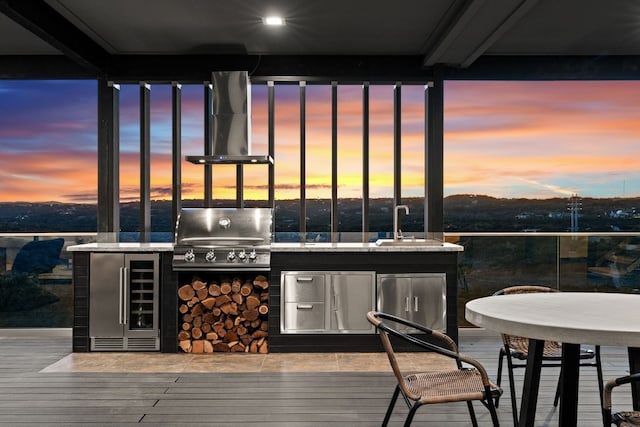 deck at dusk with wine cooler, sink, area for grilling, and exterior kitchen