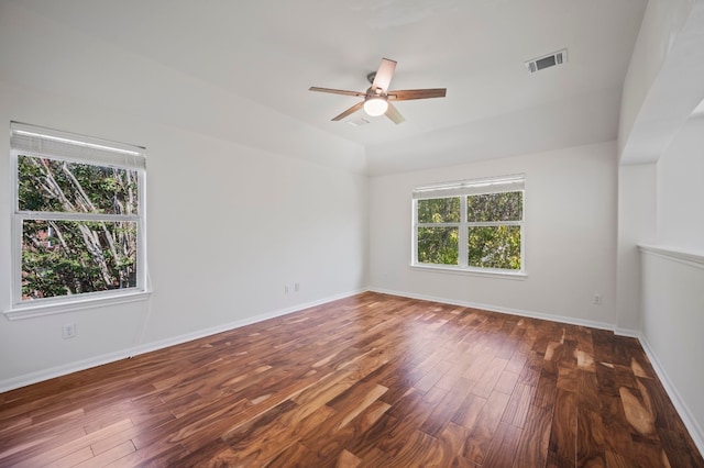 spare room featuring a wealth of natural light, ceiling fan, and dark wood-type flooring