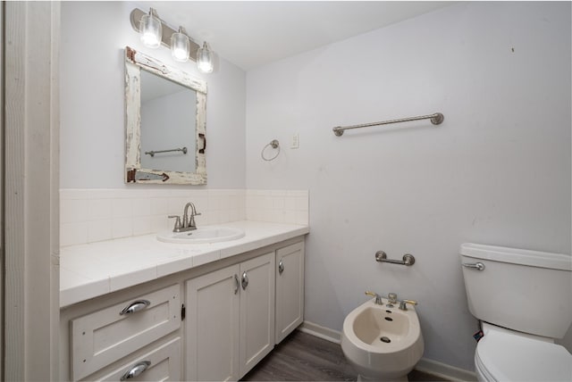 bathroom featuring backsplash, hardwood / wood-style floors, a bidet, toilet, and vanity