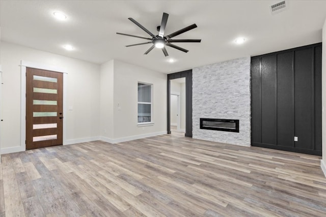 unfurnished living room with ceiling fan, a fireplace, and light hardwood / wood-style floors