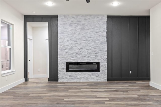 unfurnished living room featuring ceiling fan, wood-type flooring, and a fireplace