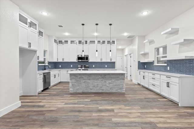 kitchen featuring a center island, sink, stainless steel appliances, decorative light fixtures, and white cabinets