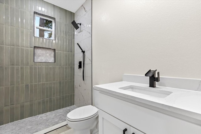 bathroom with toilet, vanity, and tiled shower