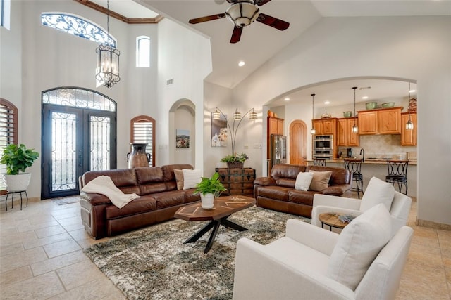 living room with a towering ceiling, sink, a notable chandelier, and french doors