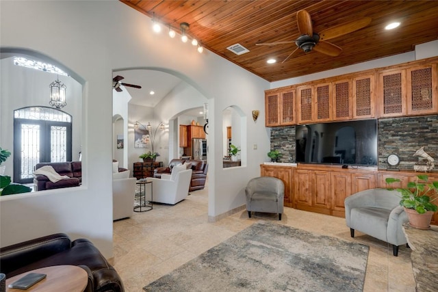 tiled living room with a high ceiling, ceiling fan with notable chandelier, and wooden ceiling