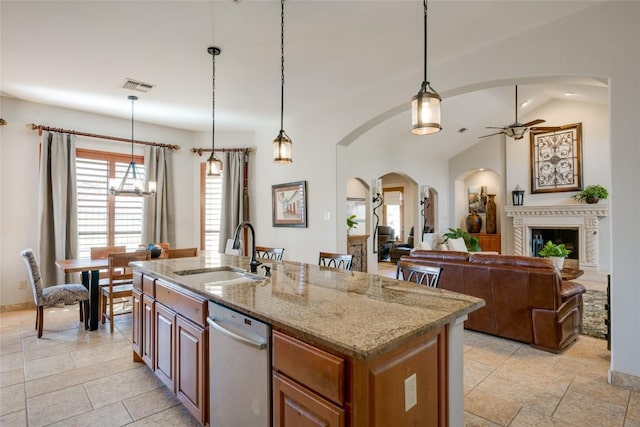 kitchen featuring sink, light stone countertops, a center island with sink, decorative light fixtures, and stainless steel dishwasher