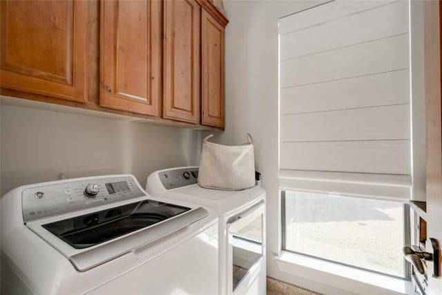 clothes washing area with cabinets and washer and clothes dryer