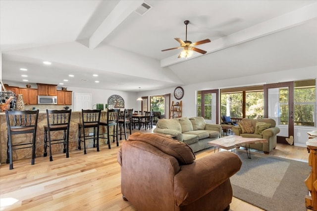 living room with lofted ceiling with beams, ceiling fan, and light wood-type flooring