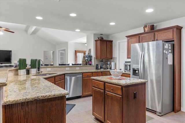 kitchen with sink, light stone counters, lofted ceiling with beams, a kitchen island, and appliances with stainless steel finishes