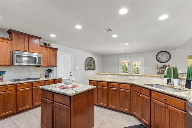 kitchen featuring sink, light tile patterned floors, hanging light fixtures, and appliances with stainless steel finishes