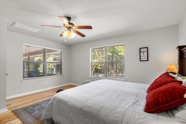 bedroom featuring light hardwood / wood-style floors, multiple windows, and ceiling fan