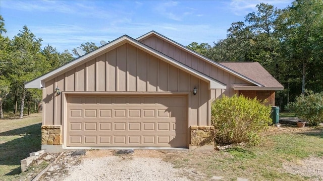 view of front of house featuring board and batten siding, an outbuilding, stone siding, and driveway