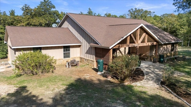 view of front of property featuring stone siding, a shingled roof, and board and batten siding