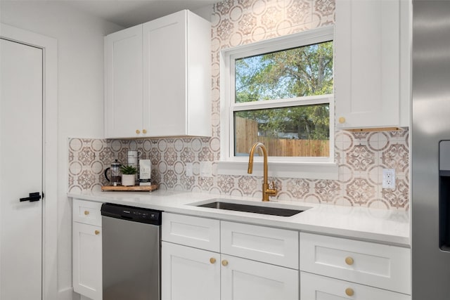 kitchen with stainless steel appliances, white cabinetry, tasteful backsplash, and sink