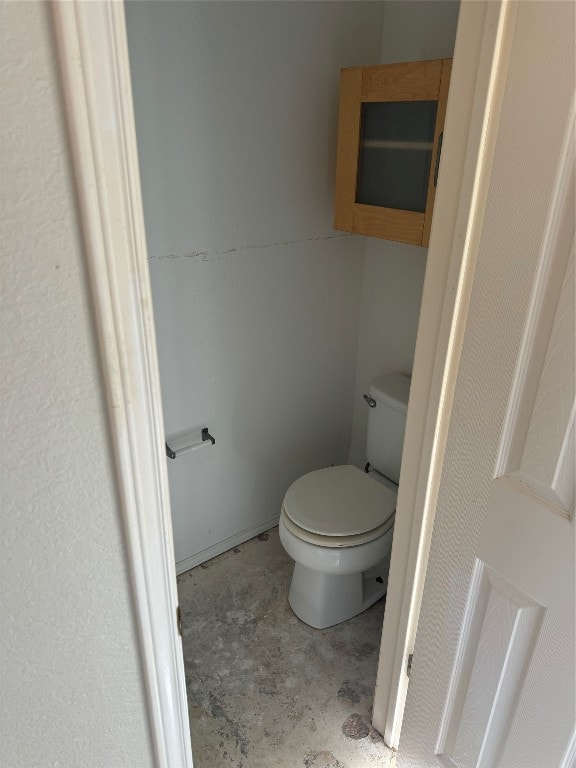 bathroom with concrete flooring and toilet