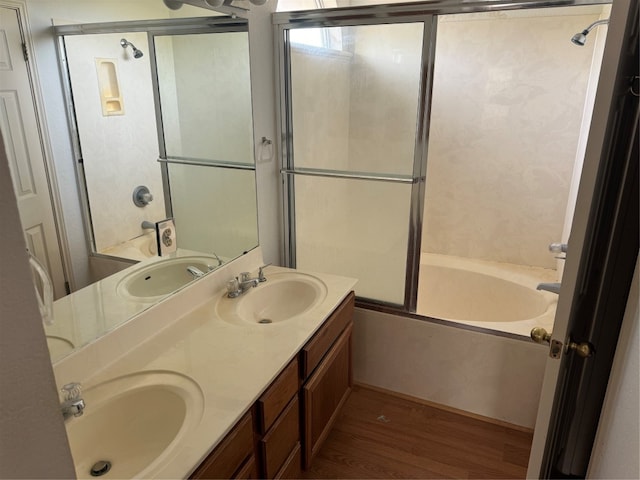 bathroom featuring hardwood / wood-style floors, vanity, and bath / shower combo with glass door