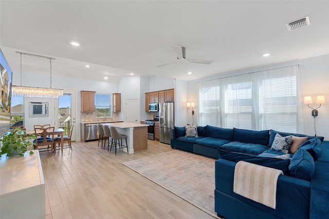 living room featuring ceiling fan, light hardwood / wood-style flooring, and plenty of natural light