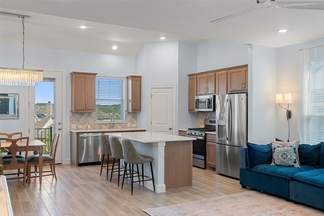 kitchen featuring a kitchen bar, appliances with stainless steel finishes, tasteful backsplash, light hardwood / wood-style floors, and a kitchen island