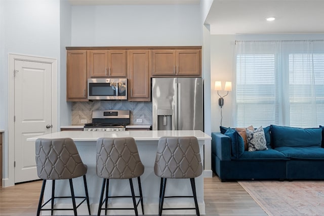 kitchen with a breakfast bar, a center island, light wood-type flooring, and appliances with stainless steel finishes