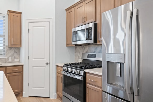 kitchen featuring appliances with stainless steel finishes, backsplash, and light hardwood / wood-style flooring