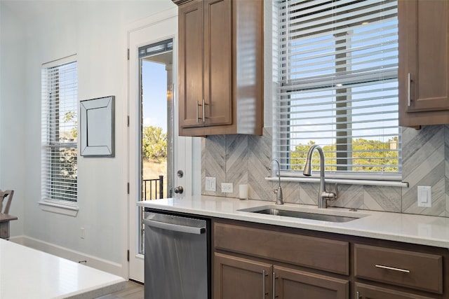 kitchen featuring stainless steel dishwasher, backsplash, sink, and a wealth of natural light