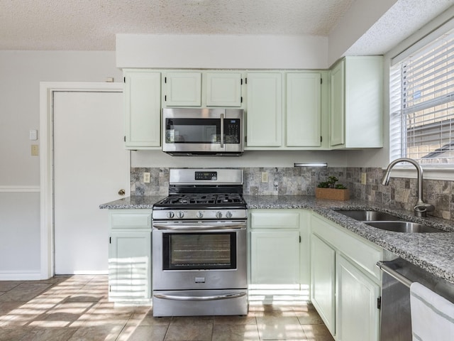 kitchen with appliances with stainless steel finishes, sink, a textured ceiling, and stone counters