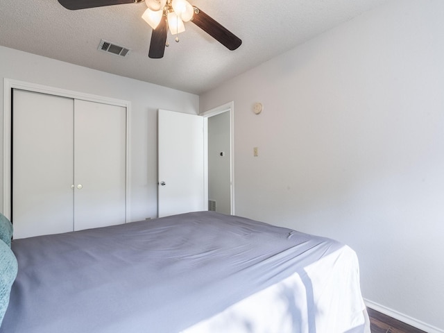 unfurnished bedroom featuring dark hardwood / wood-style flooring, a textured ceiling, ceiling fan, and a closet