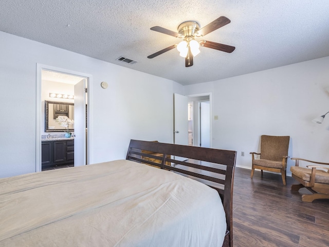 bedroom featuring dark hardwood / wood-style floors, a textured ceiling, ceiling fan, and ensuite bath