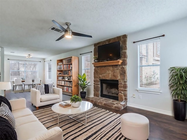 living room featuring a fireplace, dark wood-type flooring, a textured ceiling, and ceiling fan