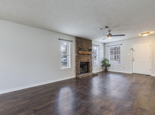 unfurnished living room featuring a textured ceiling, a fireplace, dark hardwood / wood-style floors, and ceiling fan