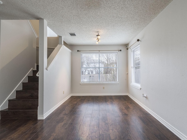 interior space featuring dark wood-type flooring, a healthy amount of sunlight, and a textured ceiling