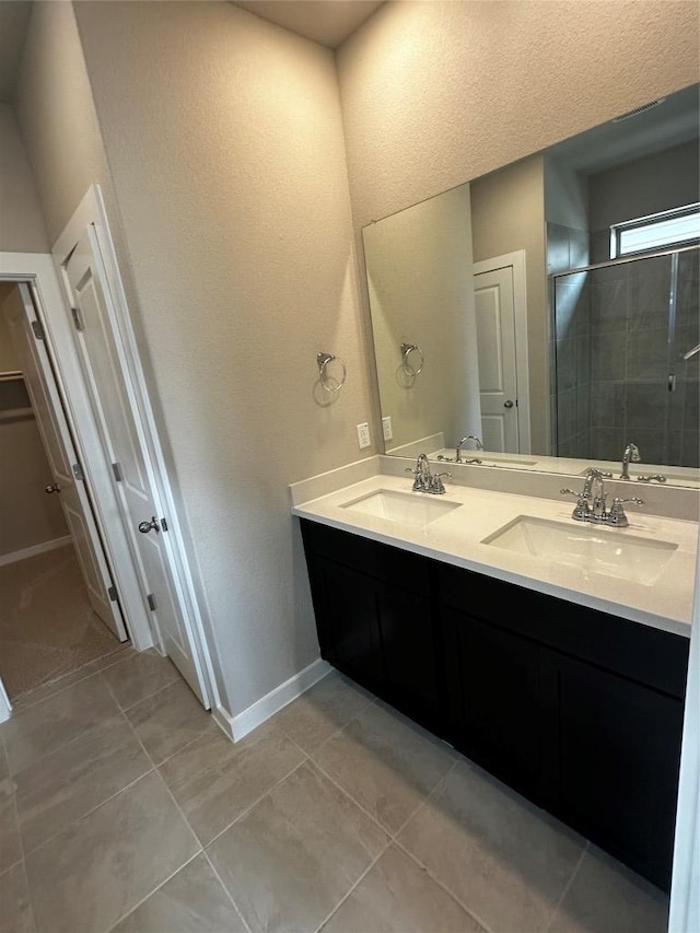 bathroom with a sink, a stall shower, double vanity, and tile patterned floors