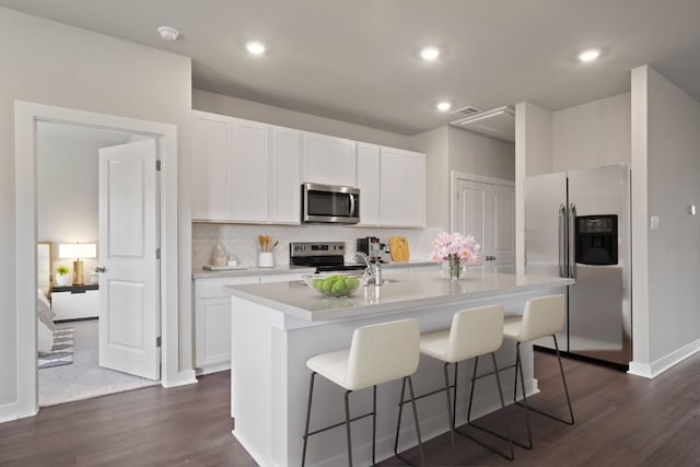 260 Lazy Lizzy Rd, Jarrell, TX 76537 - kitchen with appliances with stainless steel finishes, dark wood-style flooring, light countertops, an island with sink, and tasteful backsplash